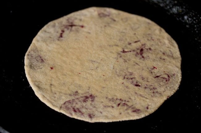 beetroot paratha placed on skillet