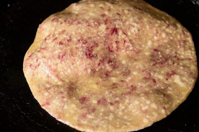 applying oil on beetroot paratha