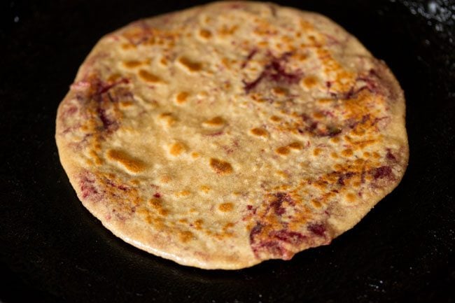 cooked beetroot paratha on skillet