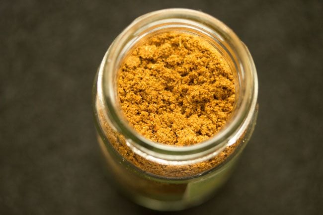 prepared biryani masala powder added to a glass jar. 