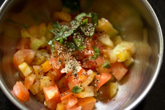 basil, garlic, and pepper added to tomatoes to make tomato bruschetta topping. 