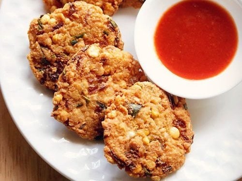 dal vada arranged neatly on a white plate next to a small white bowl of red chutney