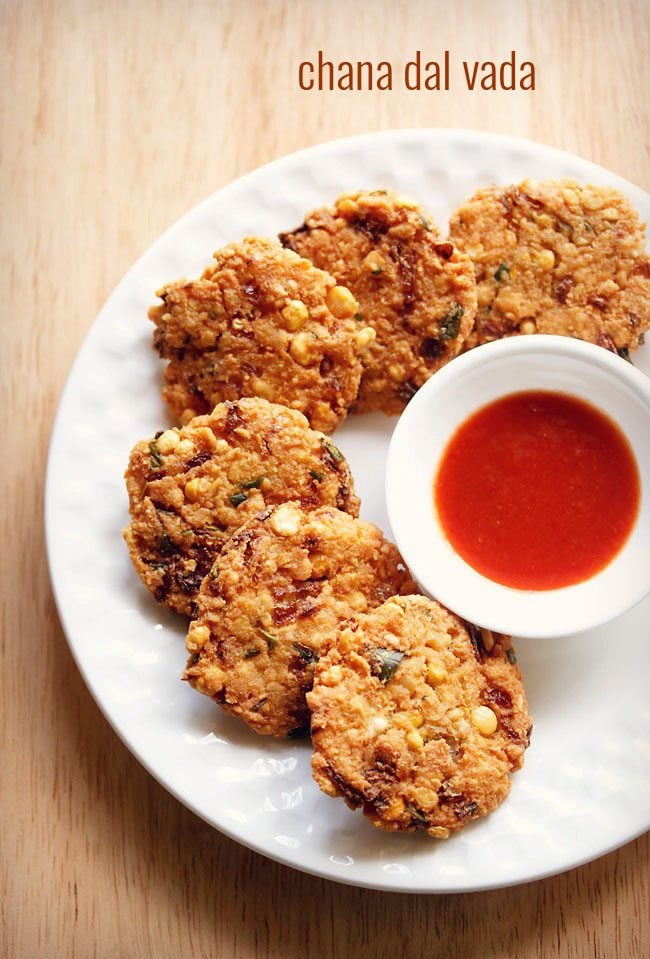 dal vada arranged neatly on a white plate next to a small white bowl of red chutney