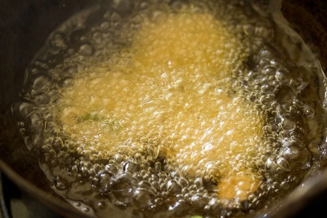 chana dal vada added to hot oil and sizzling and getting fried