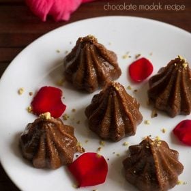 chocolate modak on a white tray garnished with rose petals