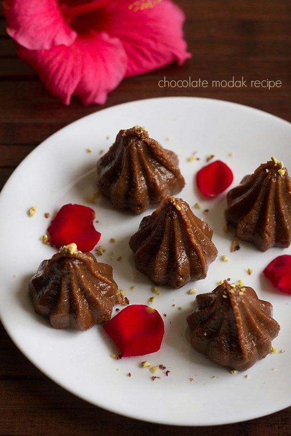 chocolate modak on a white tray garnished with rose petals