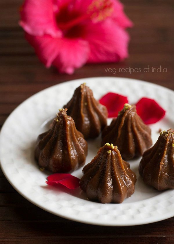 chocolate modak on a white tray garnished with rose petals