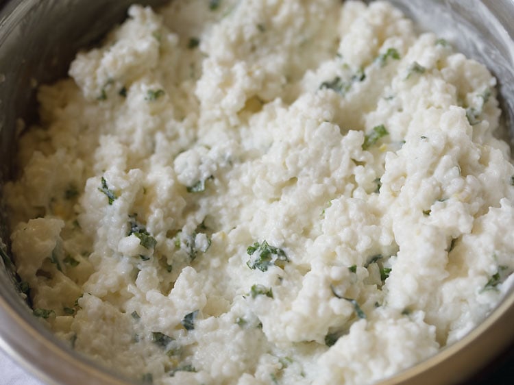 mixing the herbs and salt in the curd rice or thayir sadam mixture.