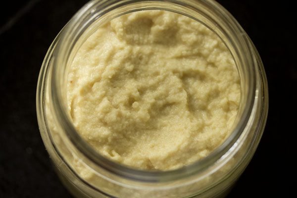 ginger garlic paste recipe in a clean glass jar on a black table. 