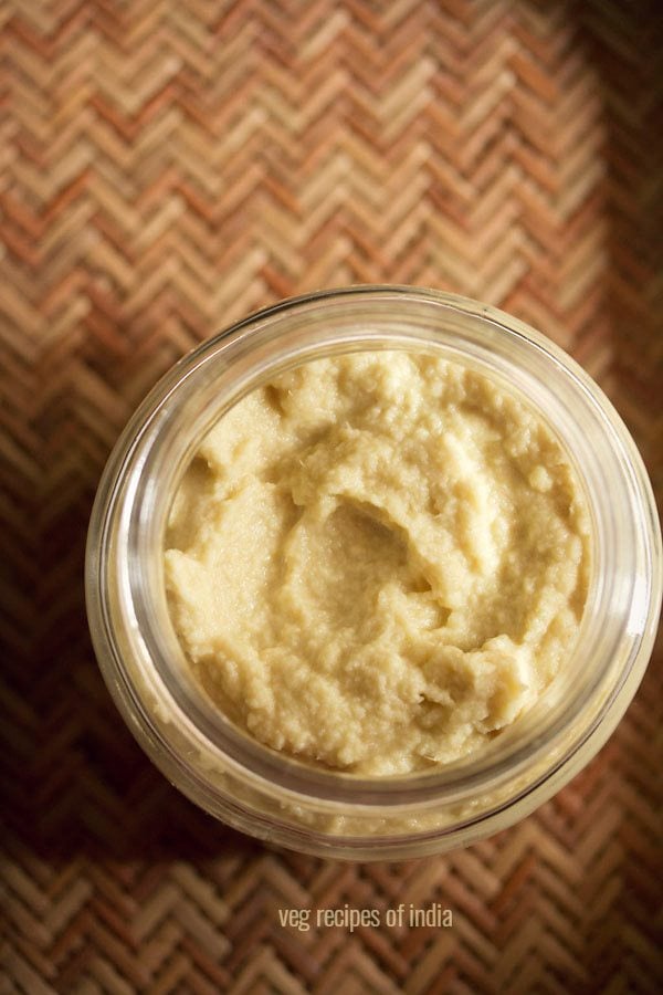 ginger garlic paste in a clear glass jar on a wooden placemat.