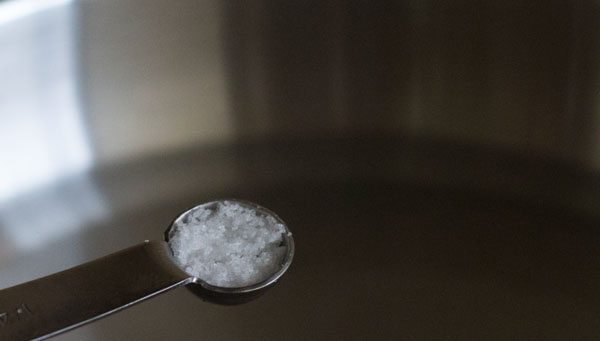 adding salt to the water in the pan. 