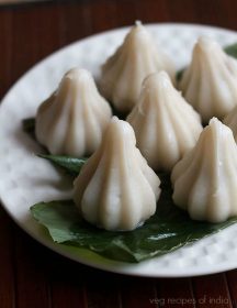 dry fruit modak on turmeric leaf on a white plate.