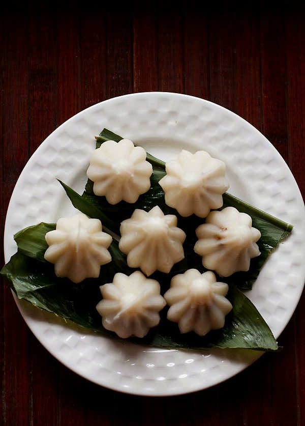 top shot of dry fruit modak placed on a turmeric leaf and served on a white plate. 