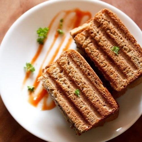 mushroom sandwich sliced and served on a white plate with ketchup.