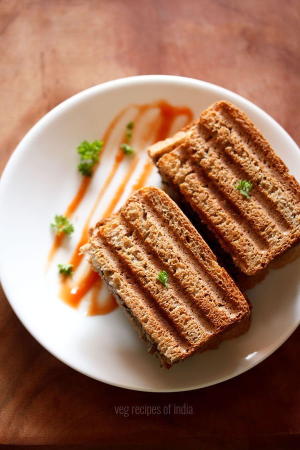 mushroom sandwich sliced and served on a plate with tomato ketchup. 