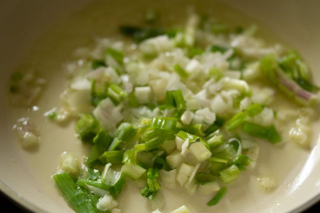 sautéing chopped spring onions with greens in the pan. 