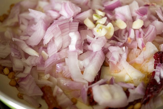 chopped onions and garlic with kashmiri red chilies and lentils in a pan