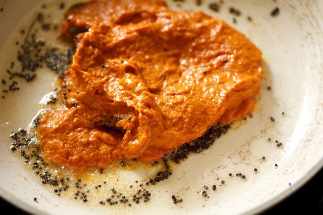 Sauteed mustard seeds, asafoetida and curry leaves with ground onion chutney in a pan