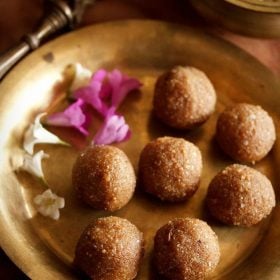 aval laddu served on a brass plate with some flowers on the side and text layover.