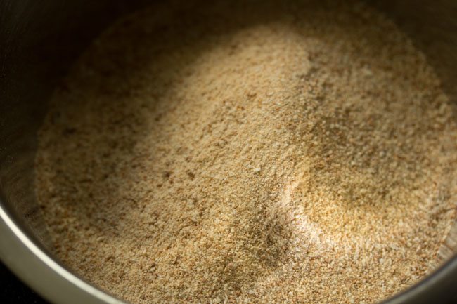 prepared poha-jaggery mixture added to a mixing bowl. 