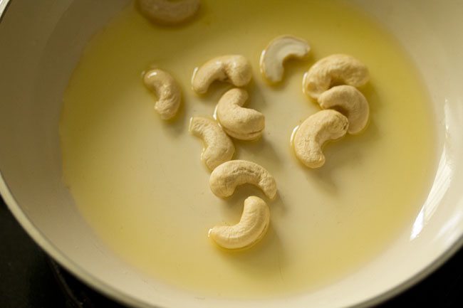 cashews added to hot ghee in pan. 