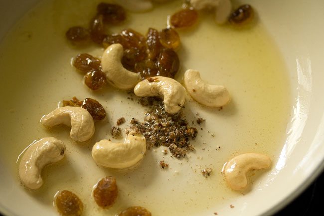 raisins and cardamom powder added to the cashews in pan. 