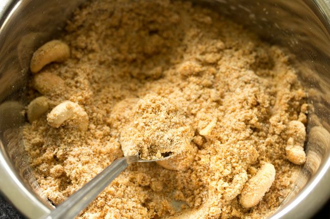 mixing ingredients with spoon to make aval laddu. 