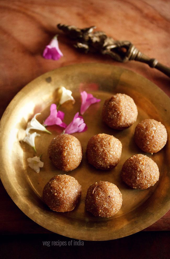 aval laddu served on a brass plate with some flowers on the side and text layover. 