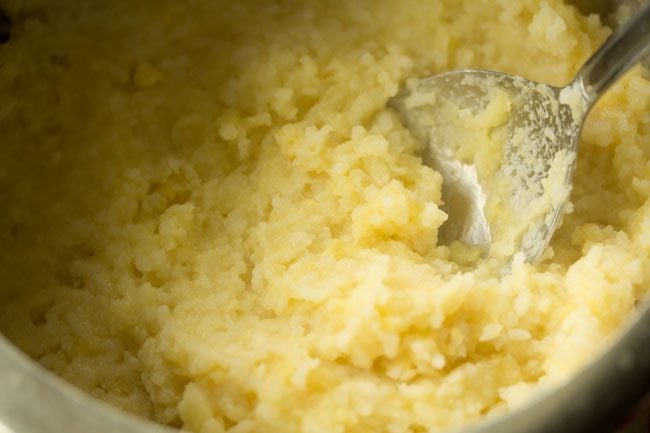 lentils and rice mashed with a spoon to make sweet pongal