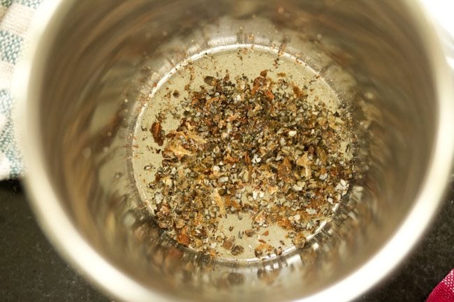 crushed cardamom and clove powder in a steel mortar