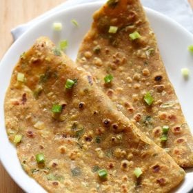 spring onion paratha folded and served on a white plate.