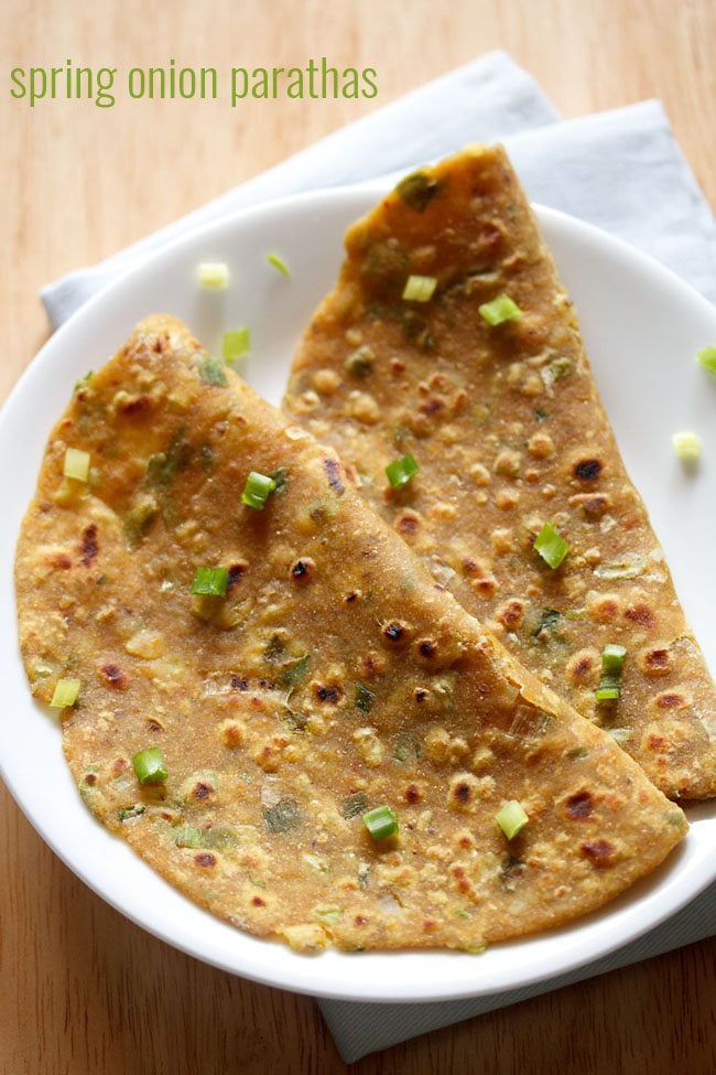 spring onion paratha folded and served on a white plate.