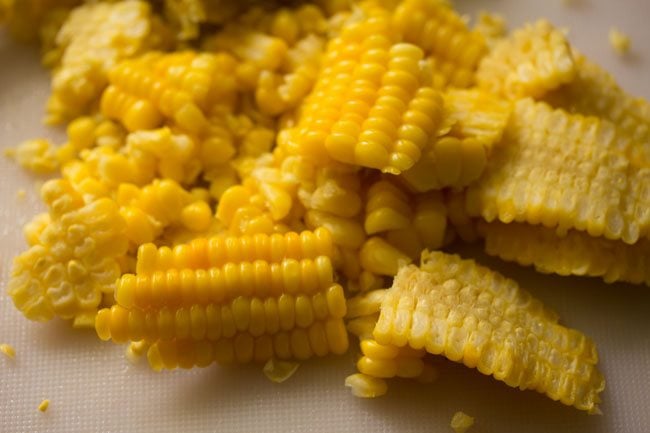 removing steamed corn kernels from the corn on cobs. 