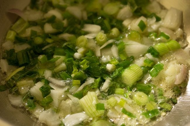 chopped spring onion whites and greens added to hot sesame oil in a wok. 