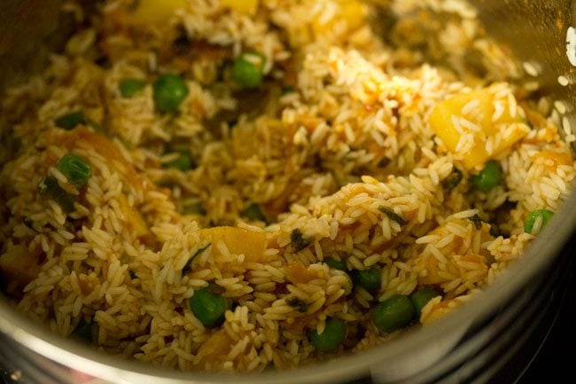 mixing rice with the rest of the tomato masala gravy