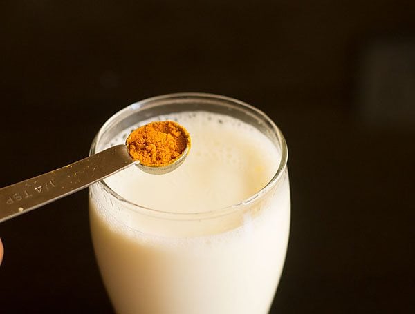 adding turmeric powder in the glass of hot milk. 