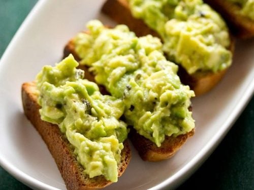 avocado toast in a white tray on a green board