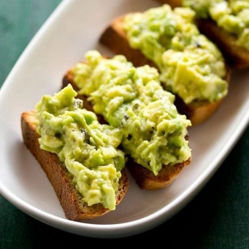 avocado toast in a white tray on a green board