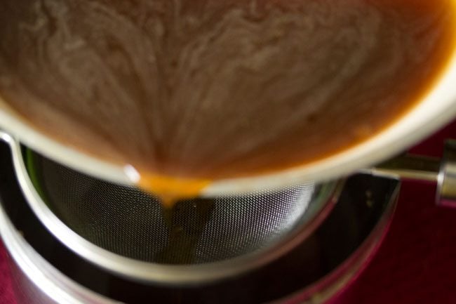 filtering jaggery syrup through a strainer. 