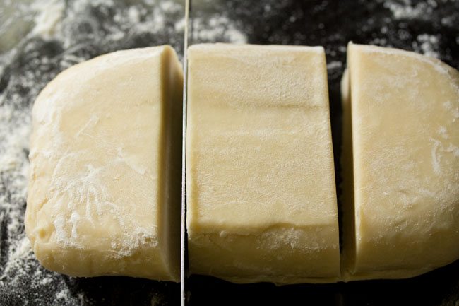 cutting rough puff pastry dough into 3 portions.