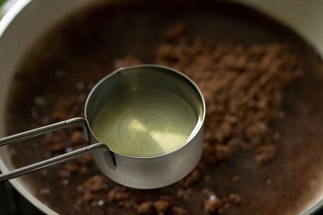 adding oil to cocoa solution for making eggless brownie. 