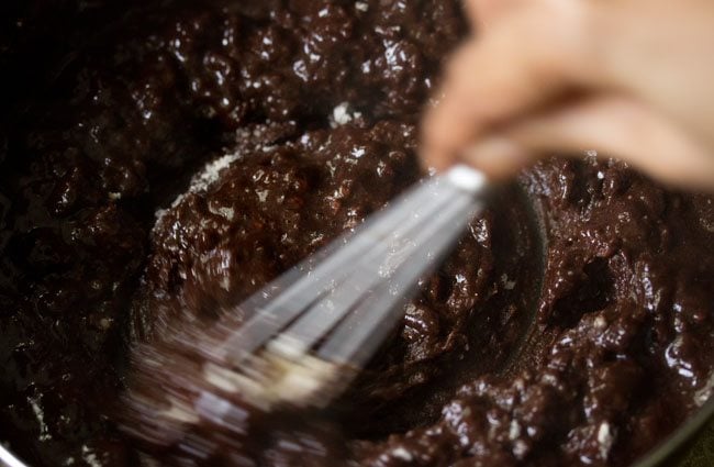 mixing ingredients with a wired whisk for eggless brownie. 