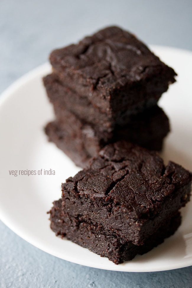 brownie cut into wedges, staked on top of each other and served on a white plate. 