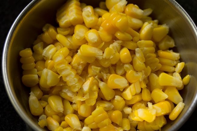 steamed corn kernels added in a bowl for masala corn recipe. 