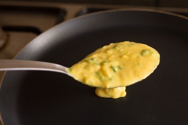 adding moong dal batter in the center of a hot pan. 