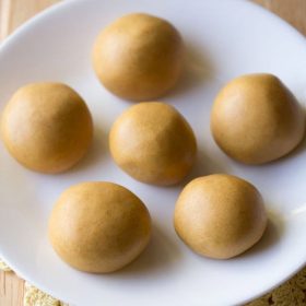 moong dal laddu served on a white plate.