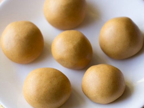 moong dal laddu served on a white plate.
