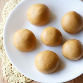 moong dal laddu served on a white plate with text layovers.