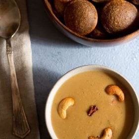 pasi paruppu payasam garnished with fried cashews and served in a white bowl.