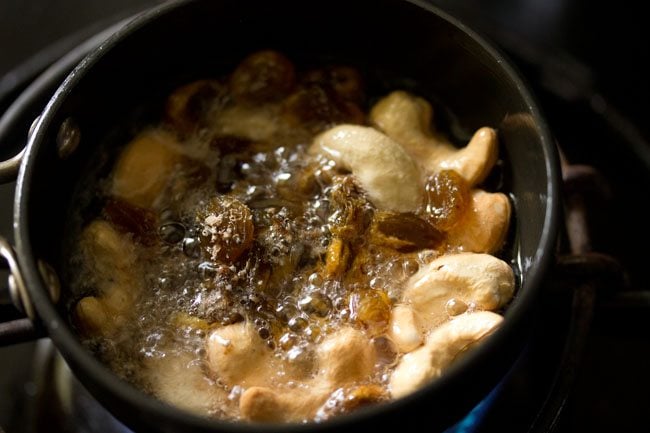 Add raisins and cardamom powder to cashews in hot oil. 